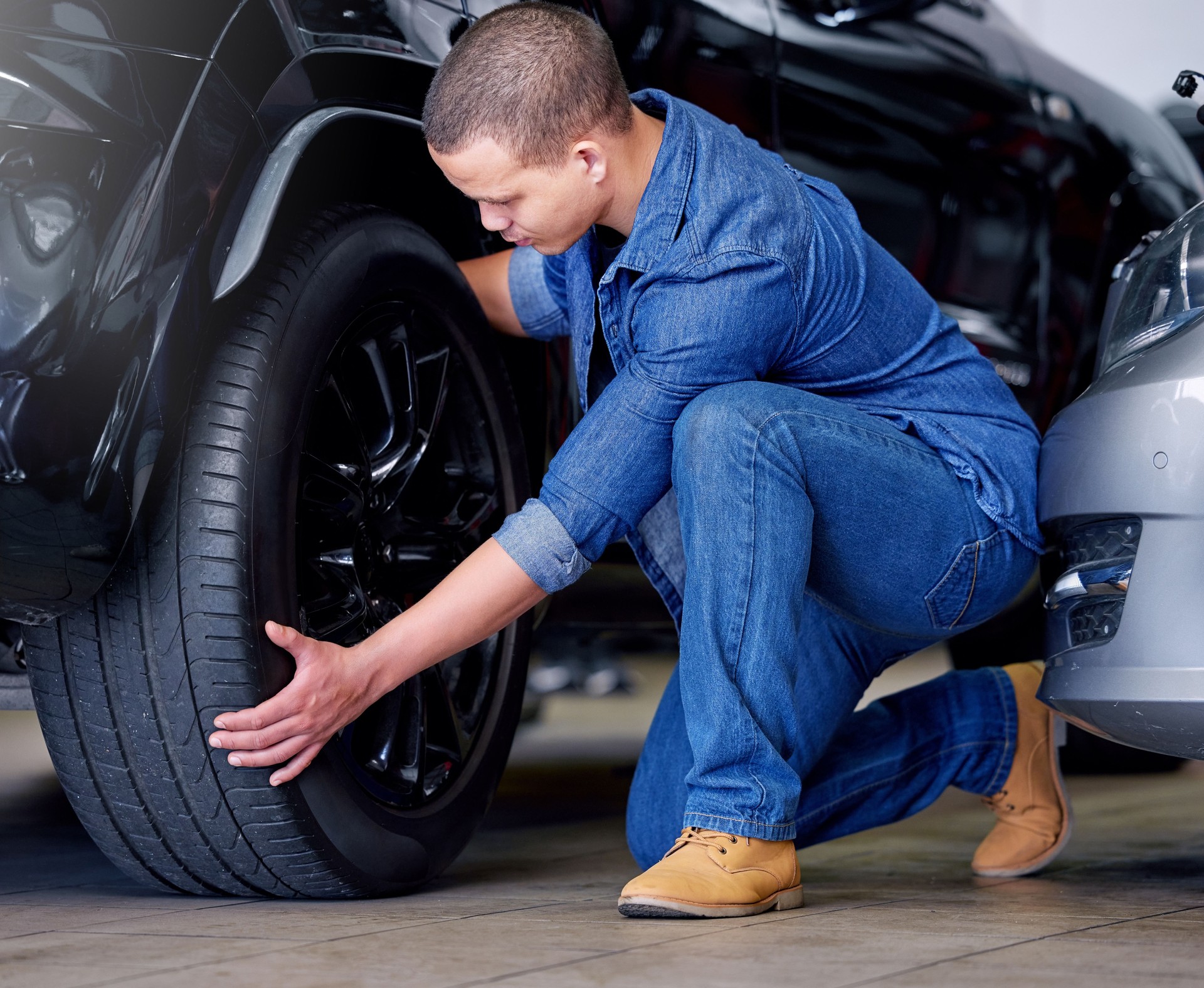 Man, car mechanic and tire change in garage, vehicle maintenance or service. Expert, professional and repairman in automobile workshop or auto shop working on wheel, tyre repair or safety inspection