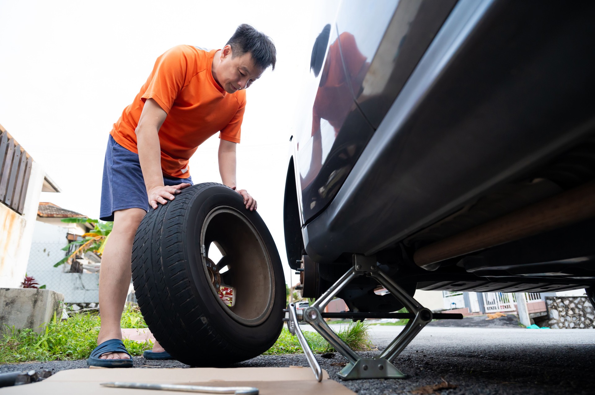 Male driver changing the wheel of a car on the roadside