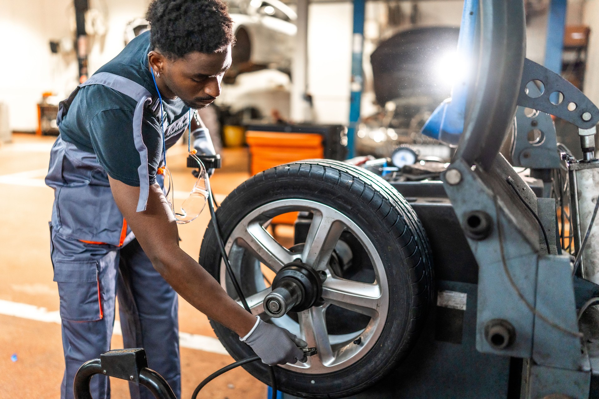 Mechanic balancing car wheel on machine in auto repair shop